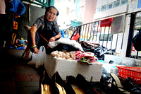 An old lady selling used items under a flyover bridge